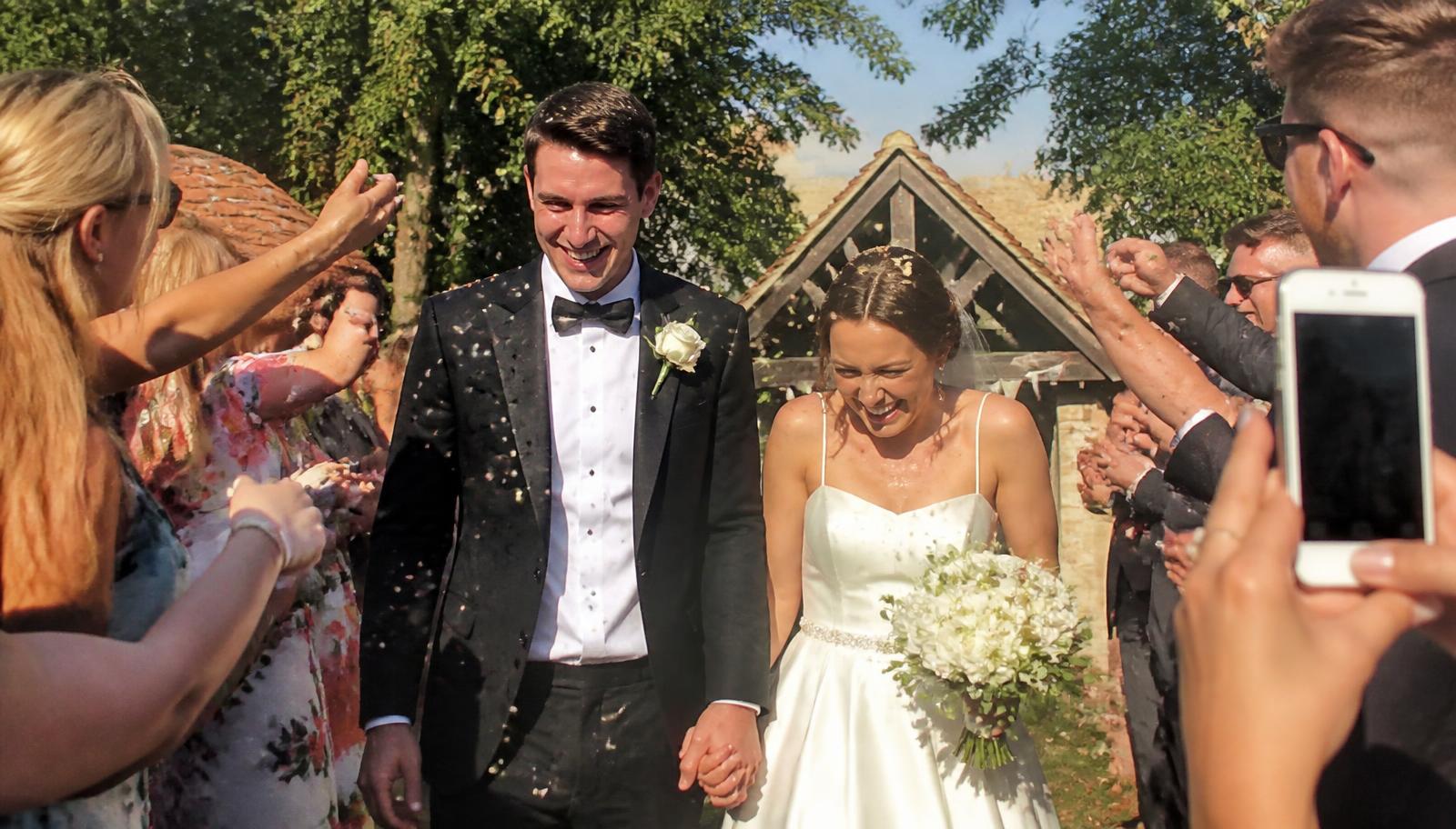 Guests throwing confetti as the newlyweds walk past